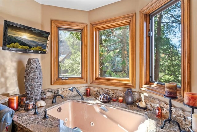 full bath featuring a tub with jets, a sink, and a healthy amount of sunlight