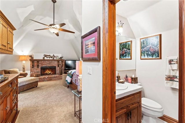 bathroom featuring a fireplace, toilet, vaulted ceiling, vanity, and ensuite bath