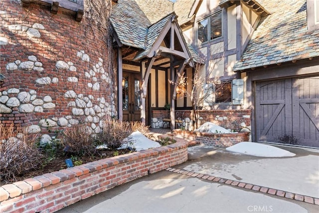 view of exterior entry with brick siding, a high end roof, and stucco siding