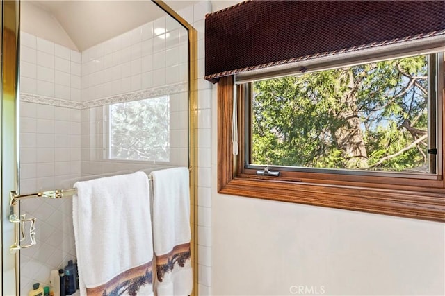 bathroom featuring vaulted ceiling and tiled shower