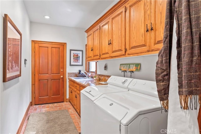 laundry area featuring brick floor, cabinet space, a sink, washer and dryer, and baseboards