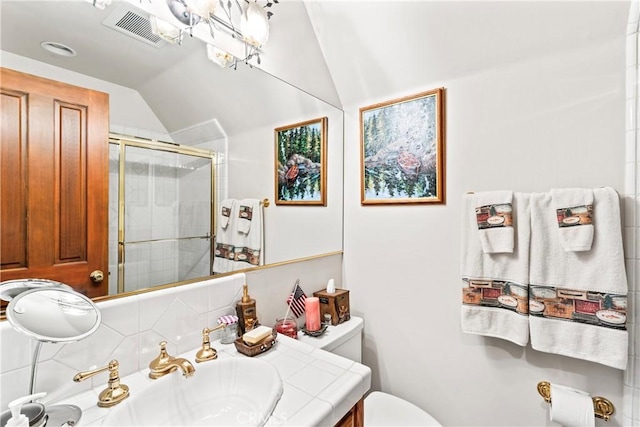 full bath with toilet, vanity, visible vents, vaulted ceiling, and a shower stall