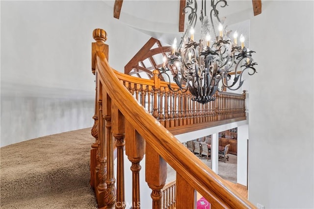 stairway featuring a high ceiling, beamed ceiling, carpet, and a notable chandelier