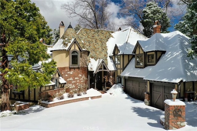 exterior space featuring a garage, brick siding, a chimney, and stucco siding