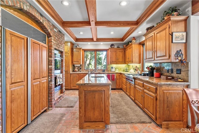 145 Pheasant Run, Lake Arrowhead, CA 92352 - kitchen featuring stainless steel appliances, a center island with sink, light stone countertops, coffered ceiling, and brown cabinetry
