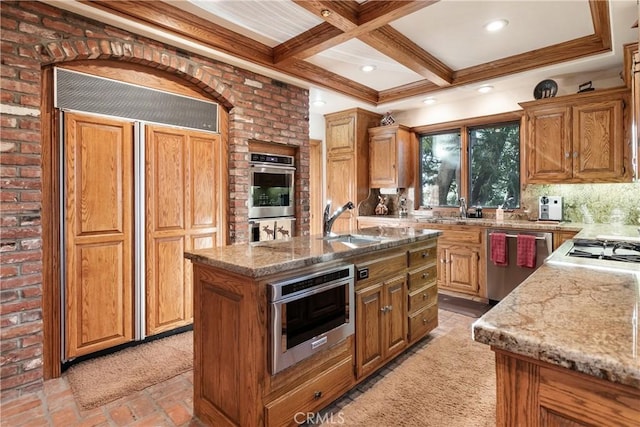 145 Pheasant Run, Lake Arrowhead, CA 92352 - kitchen featuring appliances with stainless steel finishes, light stone counters, beamed ceiling, a kitchen island with sink, and coffered ceiling