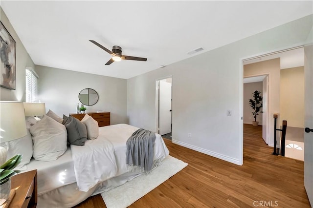 bedroom featuring visible vents, ceiling fan, baseboards, and wood finished floors