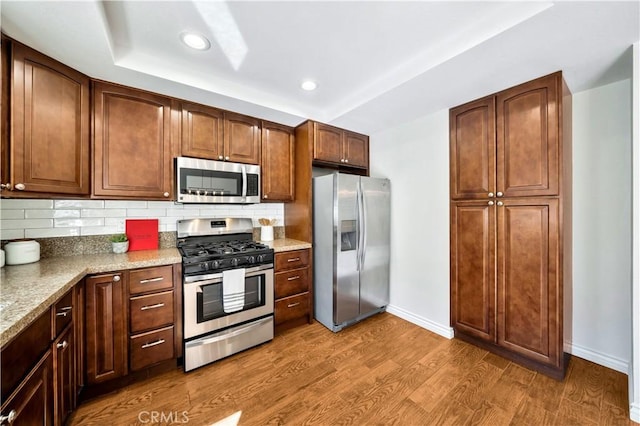 kitchen with tasteful backsplash, baseboards, recessed lighting, wood finished floors, and stainless steel appliances