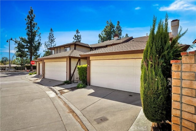 view of front of property with roof with shingles, an attached garage, driveway, and stucco siding