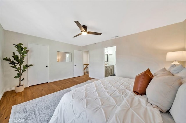 bedroom featuring a ceiling fan, wood finished floors, visible vents, baseboards, and connected bathroom