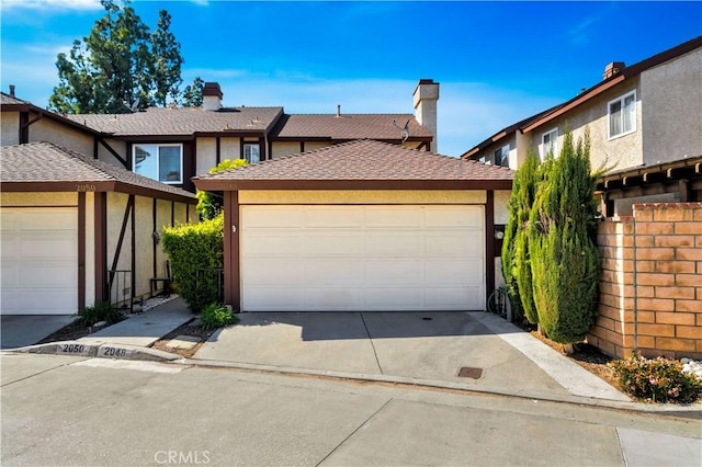 view of property featuring stucco siding, a detached garage, and a shingled roof