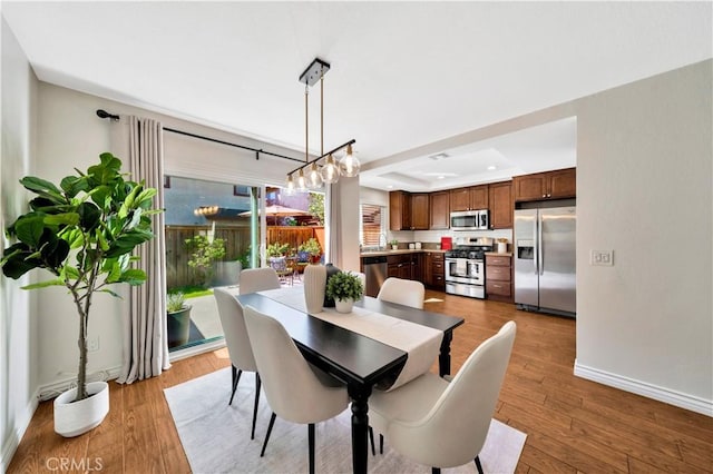 dining space with recessed lighting, a raised ceiling, baseboards, and hardwood / wood-style flooring