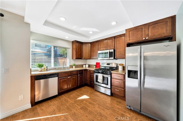 kitchen with a sink, wood finished floors, recessed lighting, appliances with stainless steel finishes, and decorative backsplash