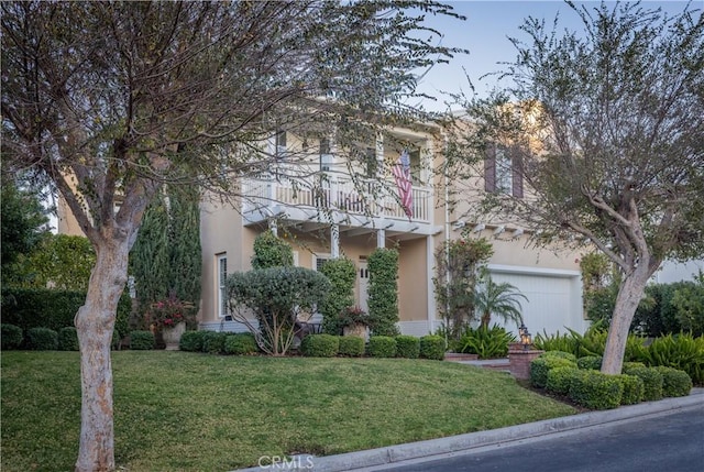 view of front facade with a front yard, a balcony, and stucco siding