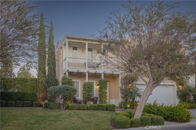 view of front of property with a front lawn, a balcony, an attached garage, and stucco siding