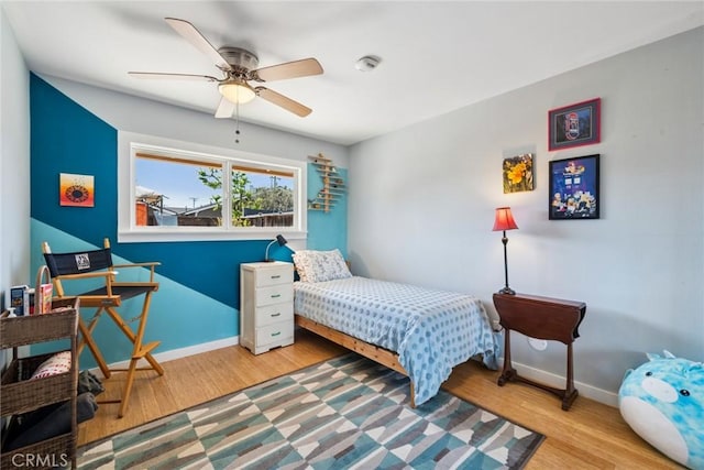 bedroom featuring ceiling fan, baseboards, and wood finished floors