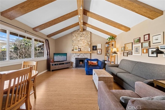 living area featuring light wood-type flooring, vaulted ceiling with beams, a stone fireplace, and baseboards