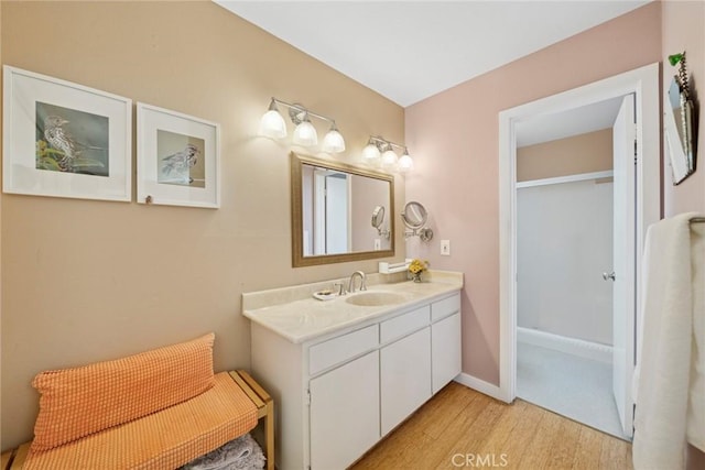 full bath with a shower with door, vanity, baseboards, and wood finished floors