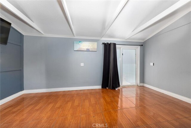 unfurnished room featuring lofted ceiling with beams and baseboards