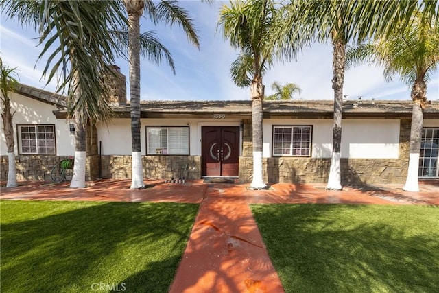 ranch-style house with a front yard, stone siding, and stucco siding