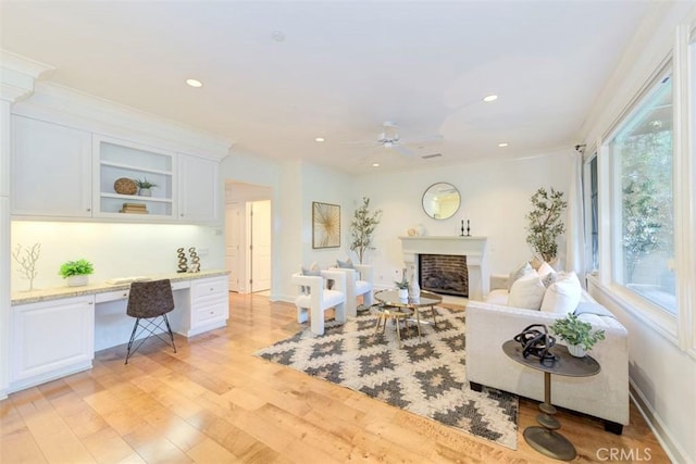 living area featuring light wood-type flooring, a fireplace, built in desk, and recessed lighting