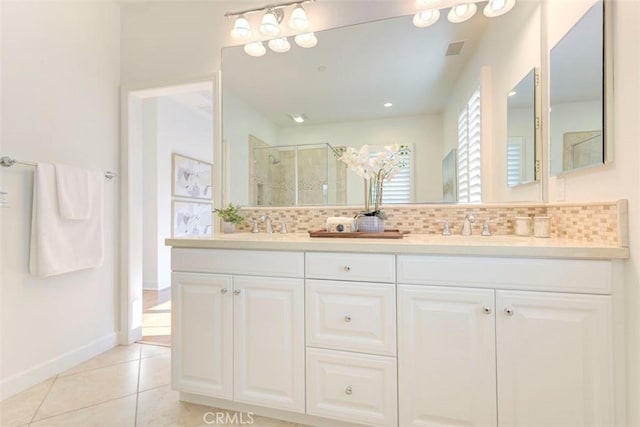 full bath featuring double vanity, tasteful backsplash, a sink, a shower stall, and tile patterned floors