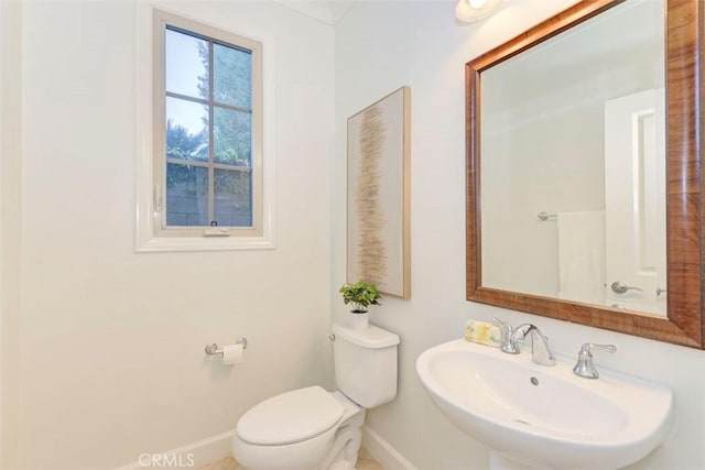 bathroom featuring toilet, baseboards, and a sink