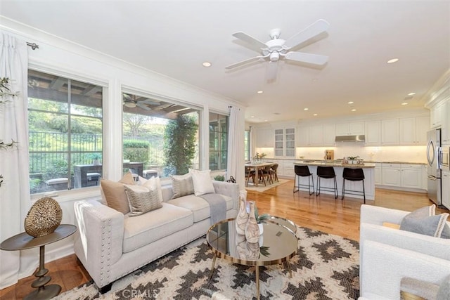 living room featuring light wood finished floors, a ceiling fan, and recessed lighting