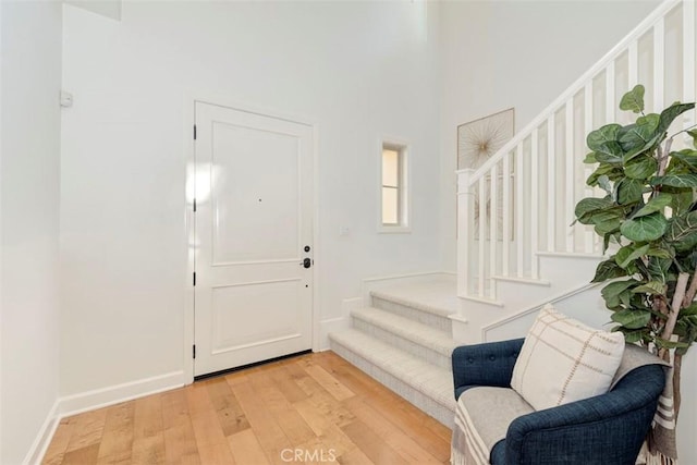 entrance foyer with stairs, light wood-type flooring, and baseboards