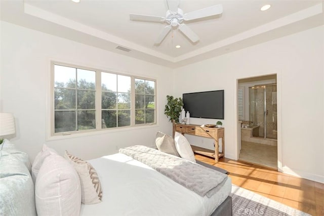 bedroom with a tray ceiling, wood finished floors, visible vents, and recessed lighting