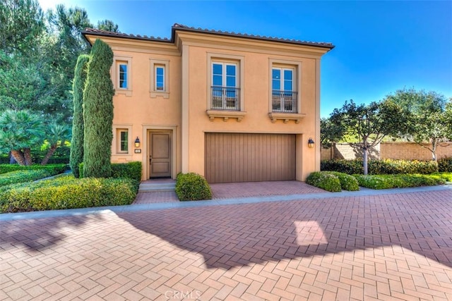 view of front of home featuring an attached garage, decorative driveway, and stucco siding