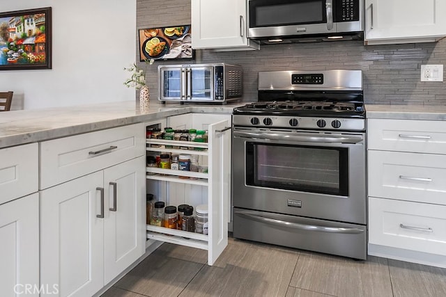 kitchen with light stone counters, a toaster, stainless steel appliances, white cabinets, and decorative backsplash