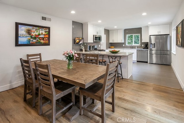 dining room featuring light wood finished floors, recessed lighting, visible vents, and baseboards