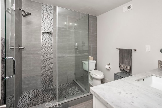 bathroom featuring visible vents, vanity, a shower stall, and toilet