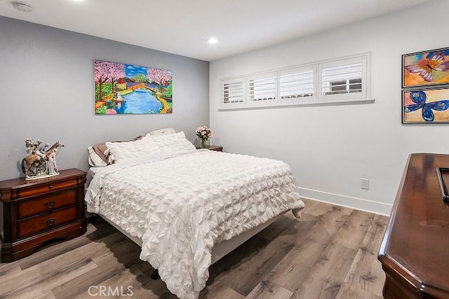 bedroom with baseboards, wood finished floors, and recessed lighting