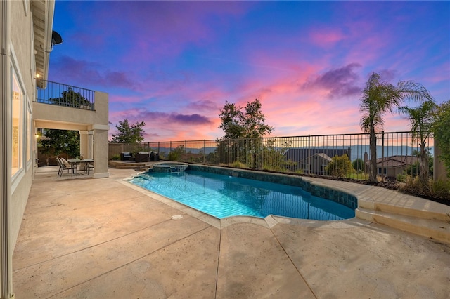 pool at dusk with a patio, fence, and a pool with connected hot tub