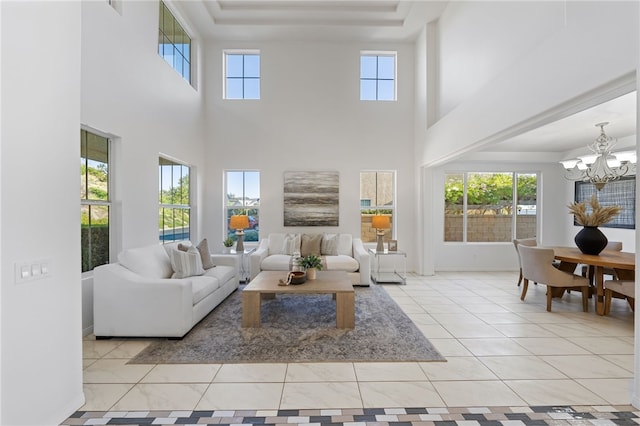 tiled living area with plenty of natural light, a raised ceiling, and a notable chandelier