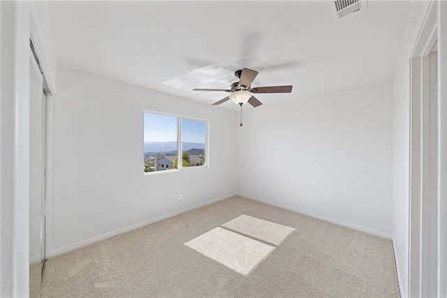 unfurnished room featuring a ceiling fan, visible vents, light carpet, and baseboards