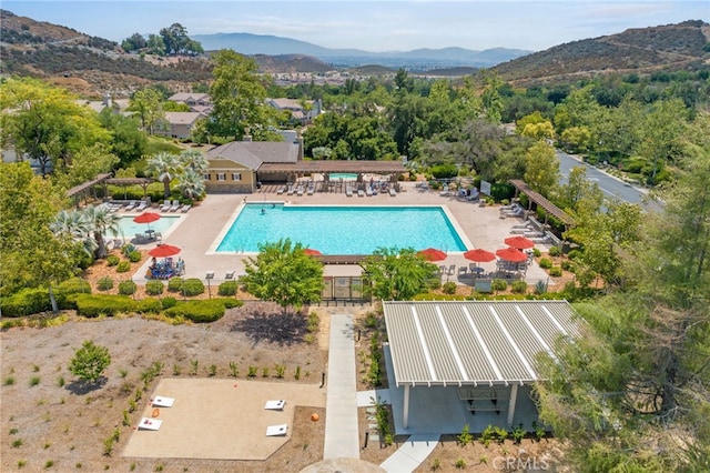 community pool featuring a patio area, a mountain view, and fence