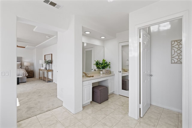 ensuite bathroom with connected bathroom, vanity, baseboards, visible vents, and tile patterned floors