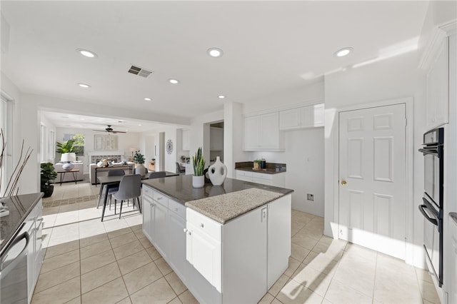 kitchen featuring light tile patterned floors, white cabinetry, a kitchen island, and visible vents