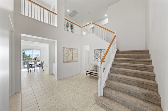 staircase with a high ceiling, tile patterned flooring, visible vents, and recessed lighting