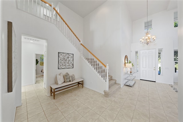 foyer featuring visible vents, a notable chandelier, a high ceiling, and stairs