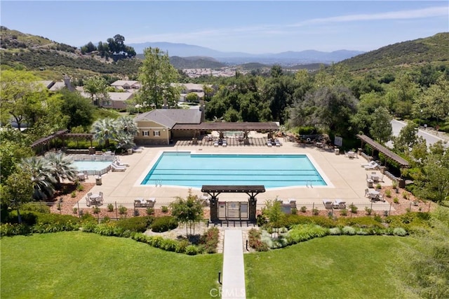 pool with a yard, fence, a mountain view, and a patio