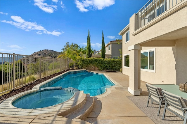 view of swimming pool with a pool with connected hot tub, a fenced backyard, a patio, and a mountain view