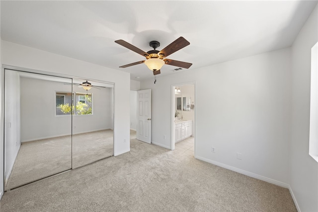 unfurnished bedroom featuring light carpet, visible vents, baseboards, a closet, and ensuite bath