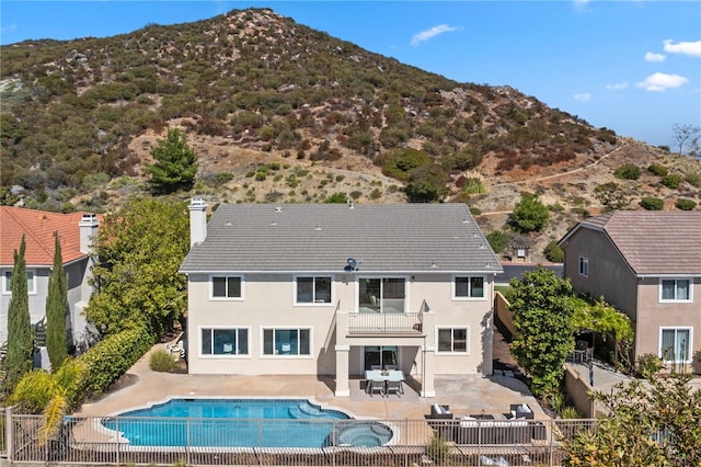 rear view of property featuring a balcony, fence, a mountain view, and a patio