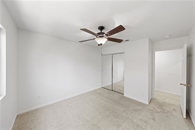 unfurnished bedroom featuring a closet, visible vents, a ceiling fan, light carpet, and baseboards