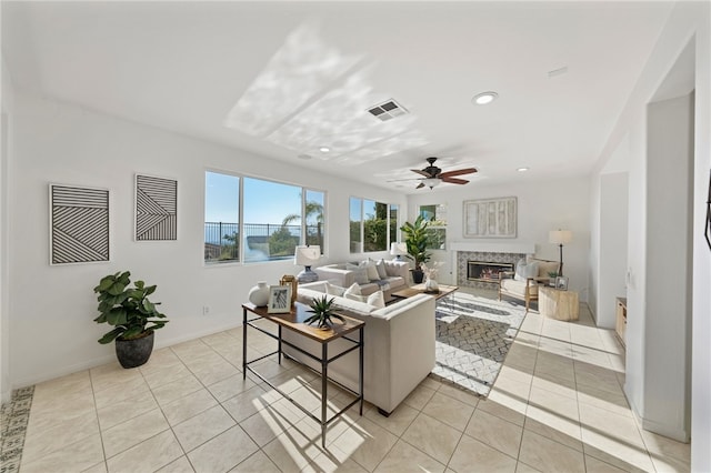 living area featuring light tile patterned floors, recessed lighting, visible vents, a ceiling fan, and a glass covered fireplace