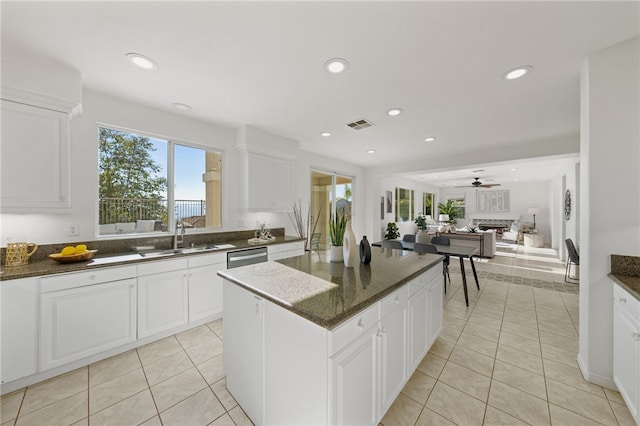 kitchen featuring visible vents, a kitchen island, a sink, a fireplace, and stainless steel dishwasher